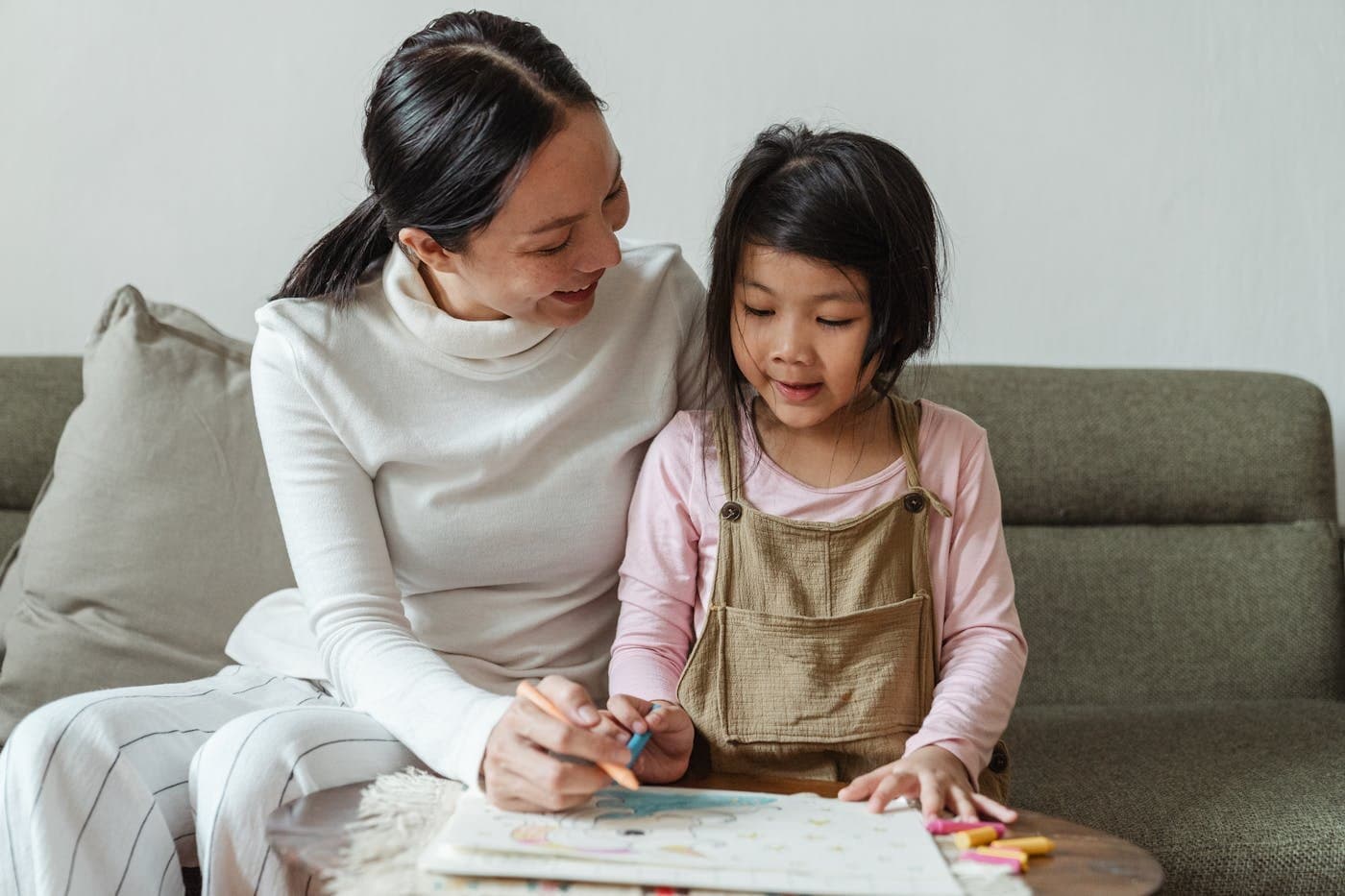 Mother and daughter drawing together on the sofa at home