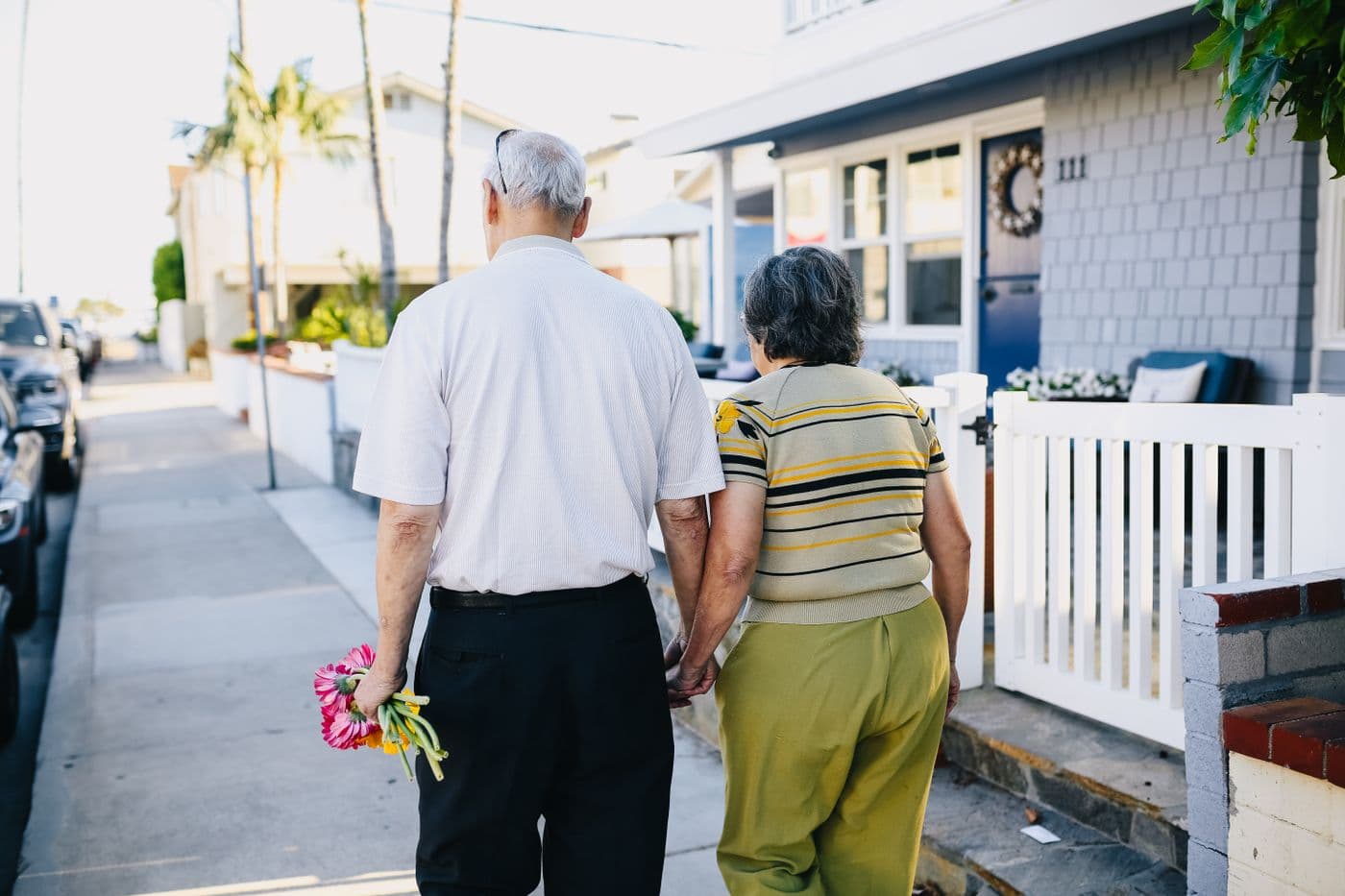 East Asian grandparents walking hand in hand outside their neighborhood home