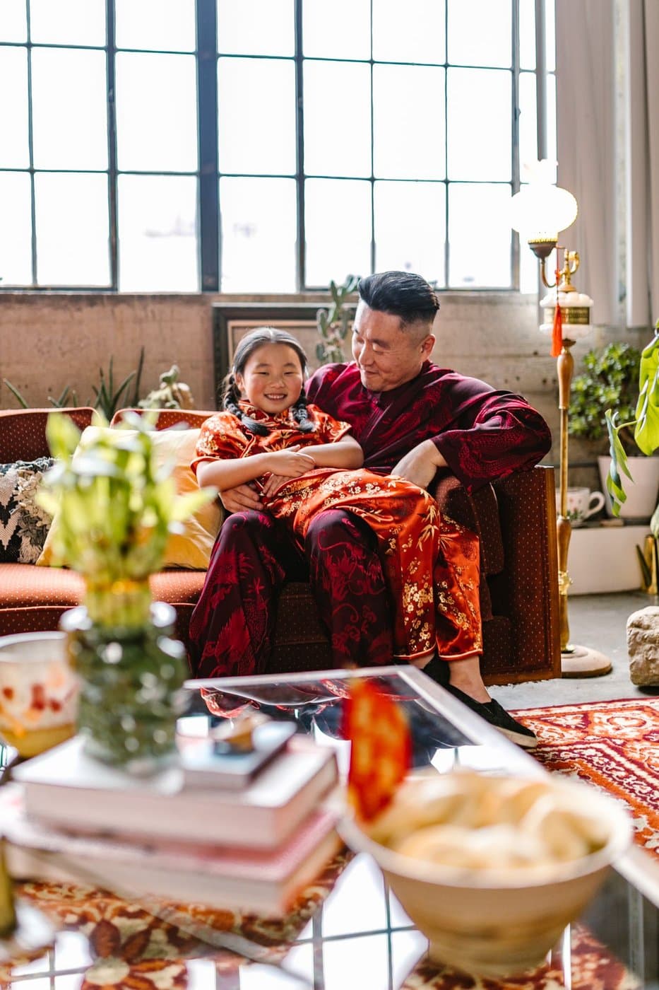 East Asian father and young daughter sharing a quiet moment on the sofa in festive clothing