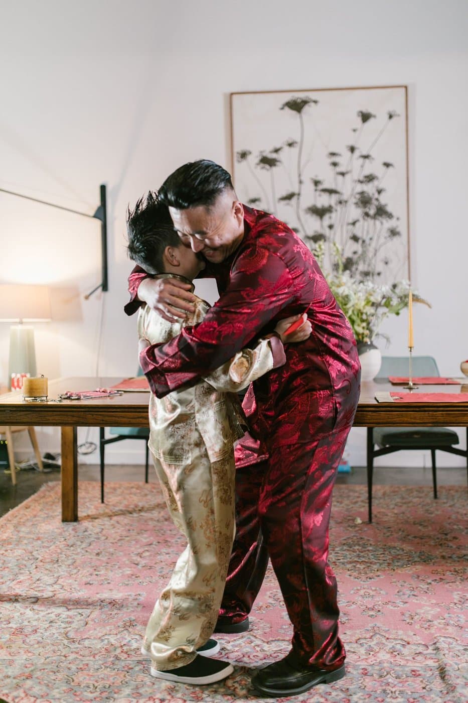 East Asian father and school-age son sharing a warm hug at home in traditional clothing