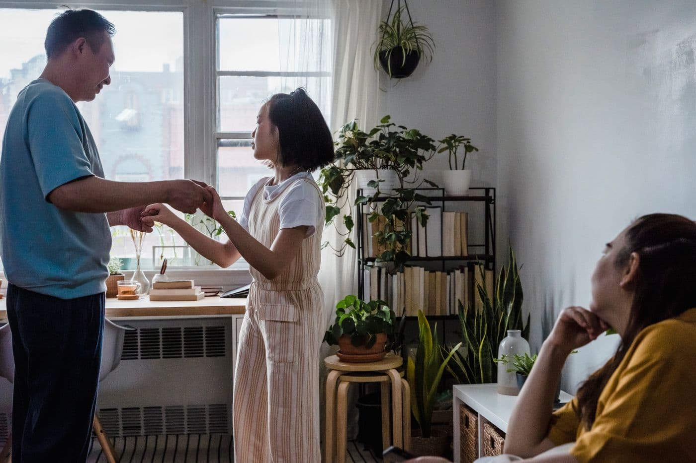East Asian mother watching her family at home while holding a smartphone