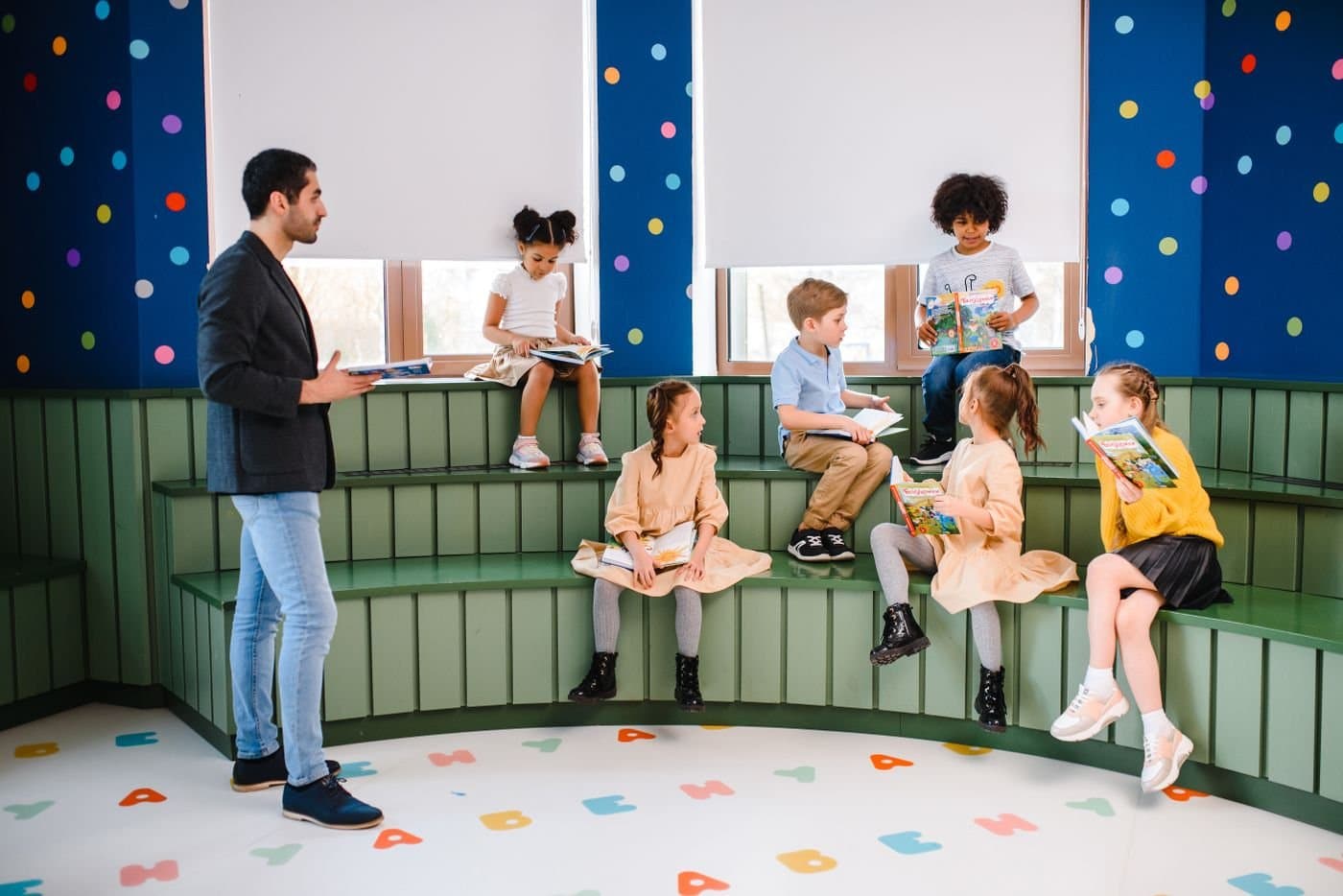 Children reading books together with a teacher in a bright classroom