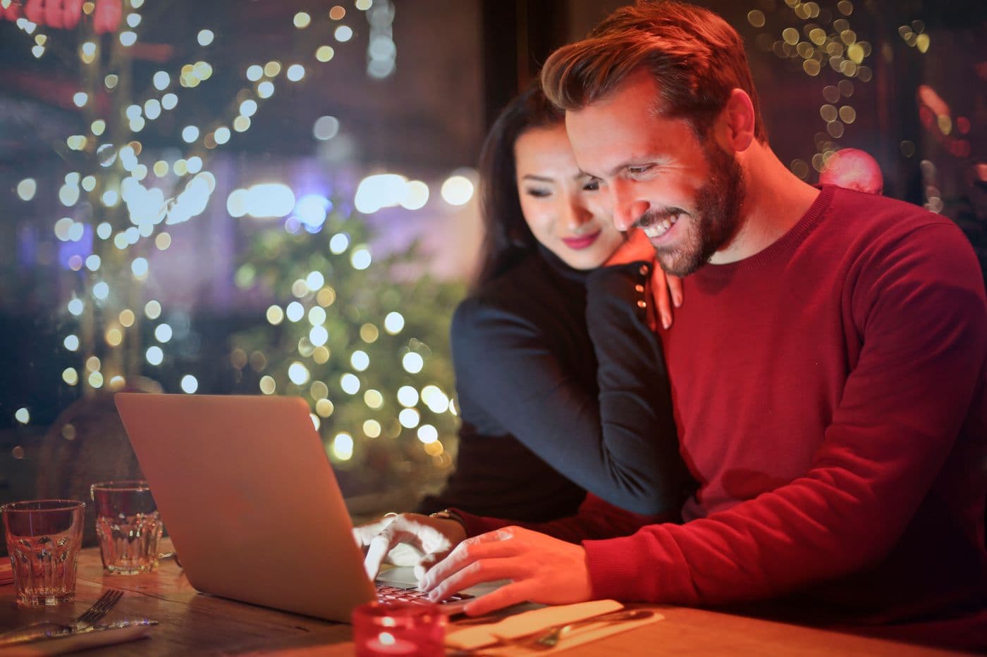 Couple reviewing plans together on a laptop at a cozy cafe