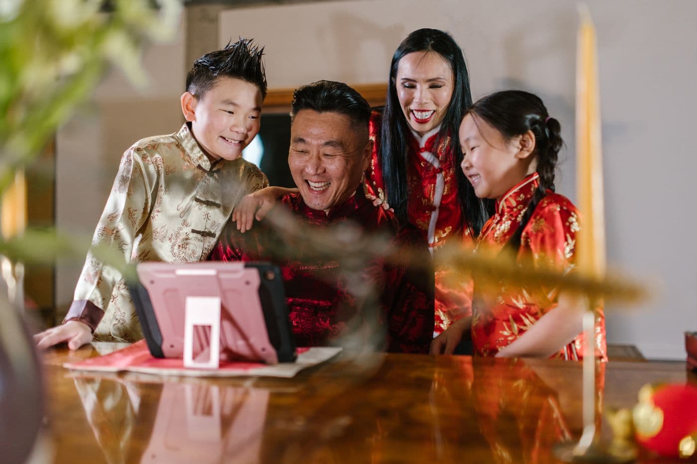 East Asian family in festive attire gathered around a tablet for a video call at home