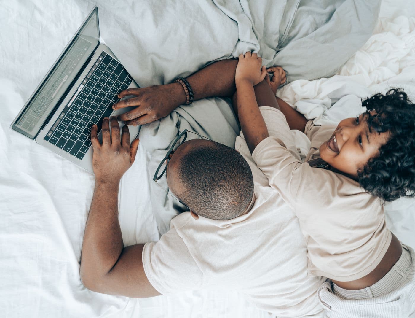 Ethnic father spending unhurried time with his young child at home on the bed