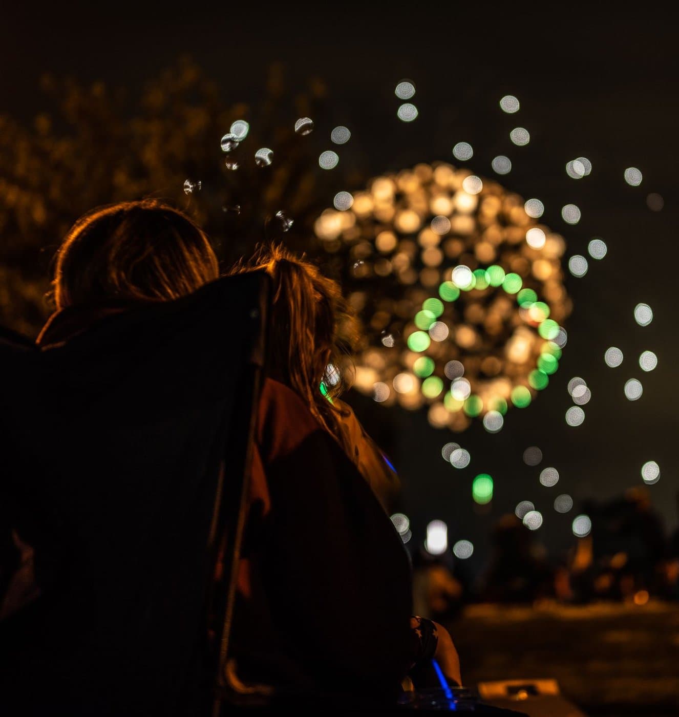 Parent and child watching fireworks together on a summer evening