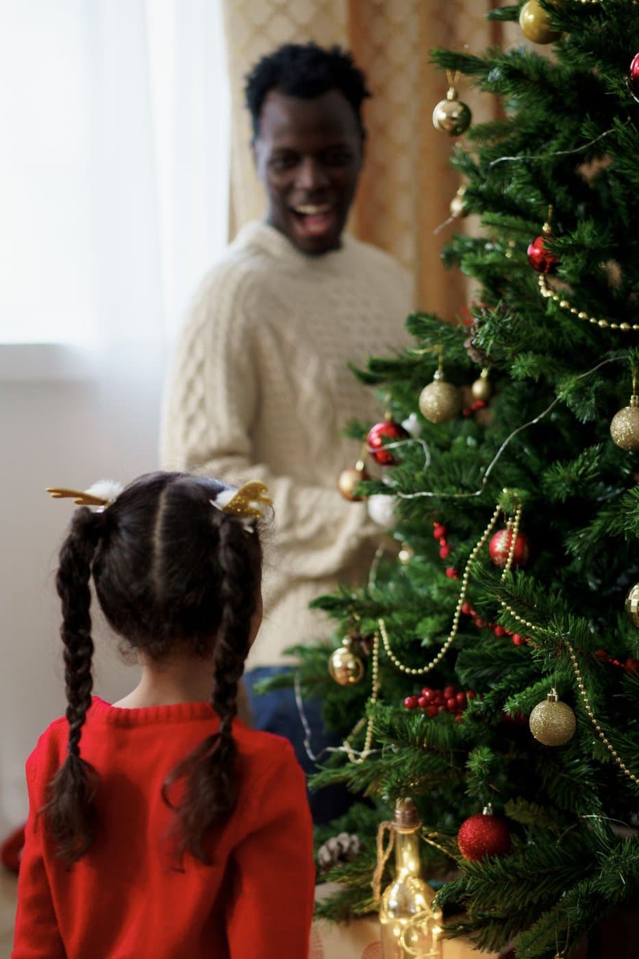 Father and daughter decorating a Christmas tree together at home