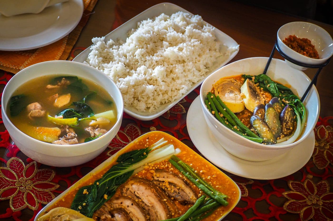 Filipino tanghalian with rice, sinigang, and kare-kare served family-style