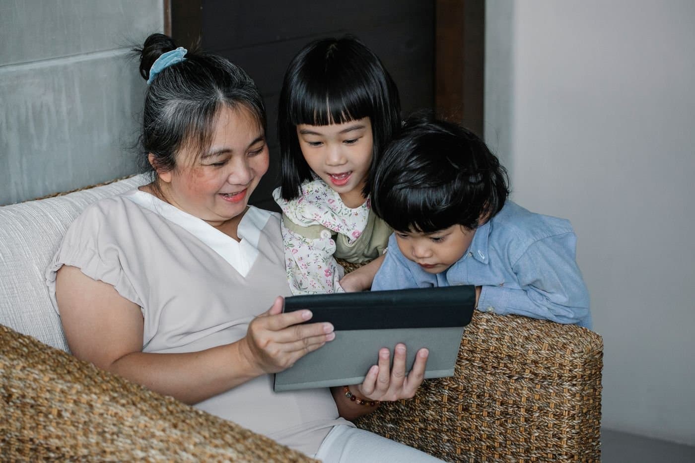 Grandmother and grandchildren gathered around a tablet at home