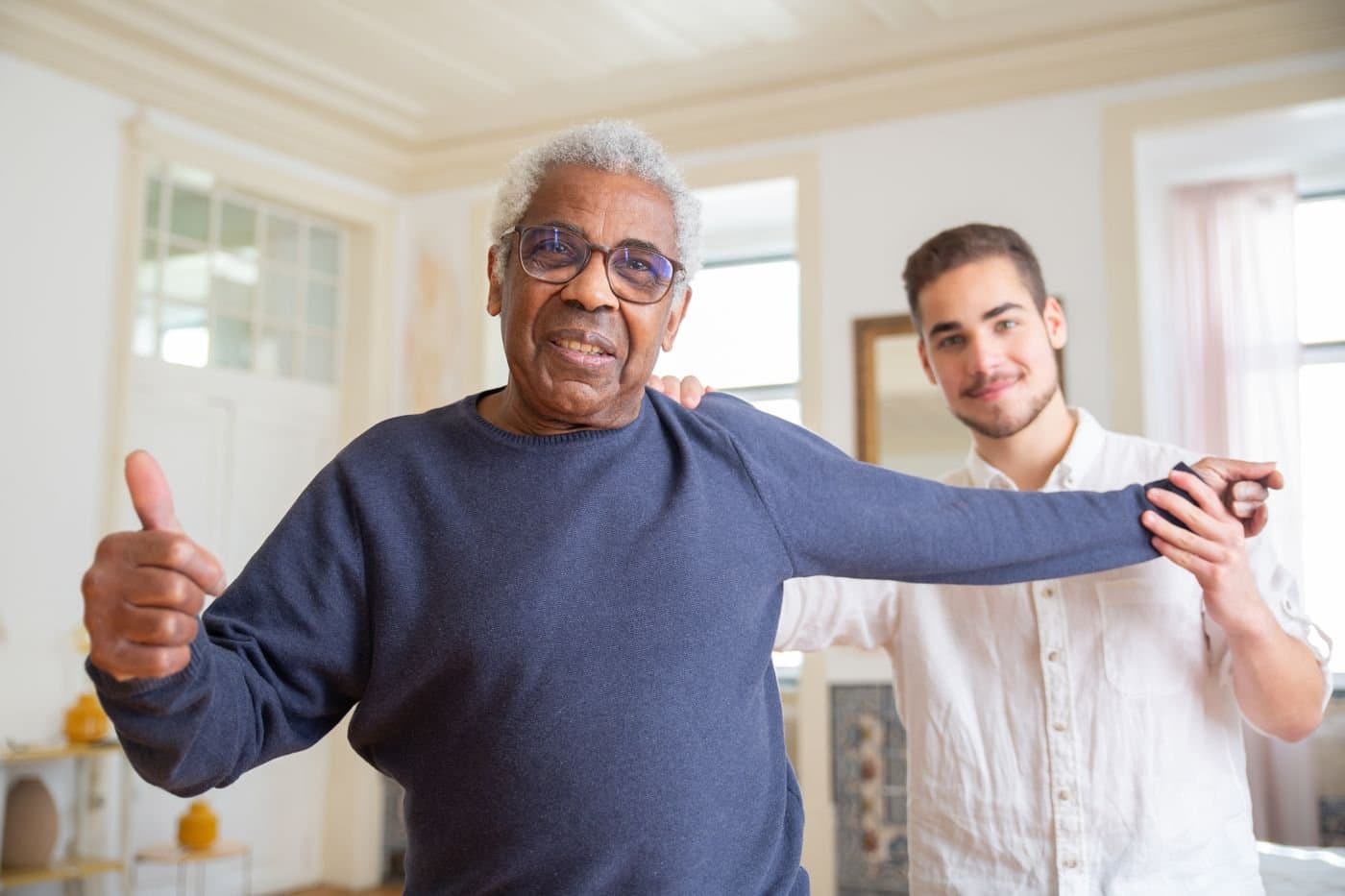 Younger family member supporting a grandparent during a mobility exercise at home