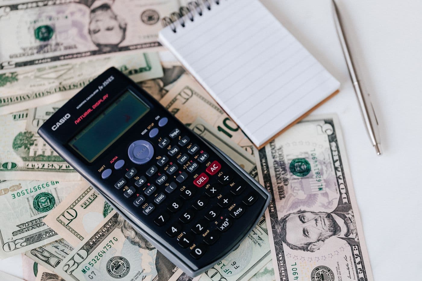 Calculator, notepad, and US currency laid out for household budget planning