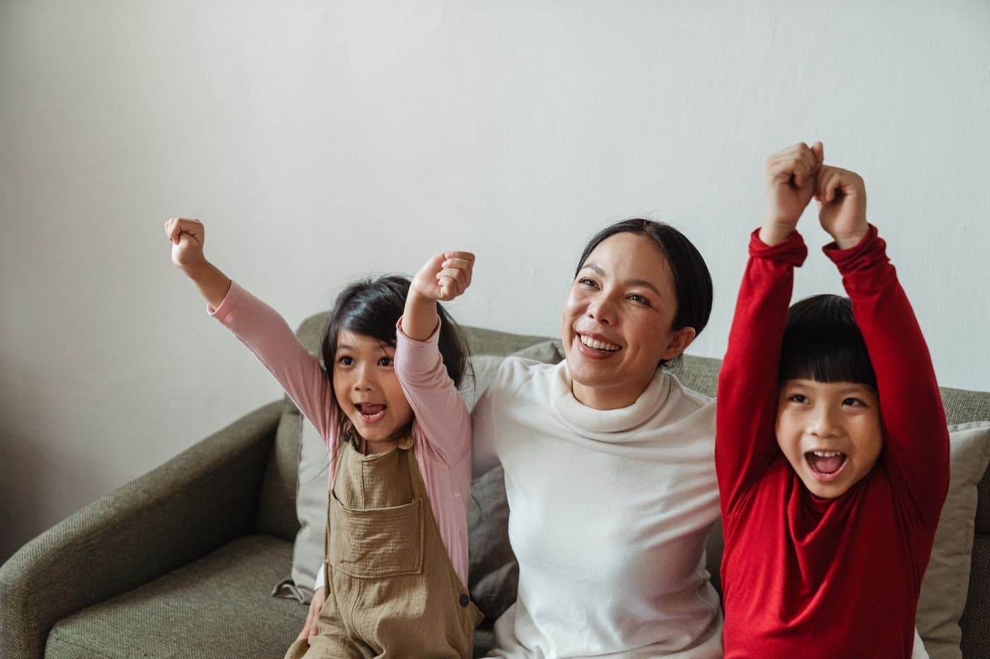 Mother and children cheering together on the living room sofa