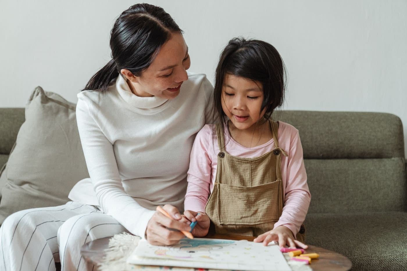 Mother and daughter drawing together on the sofa at home