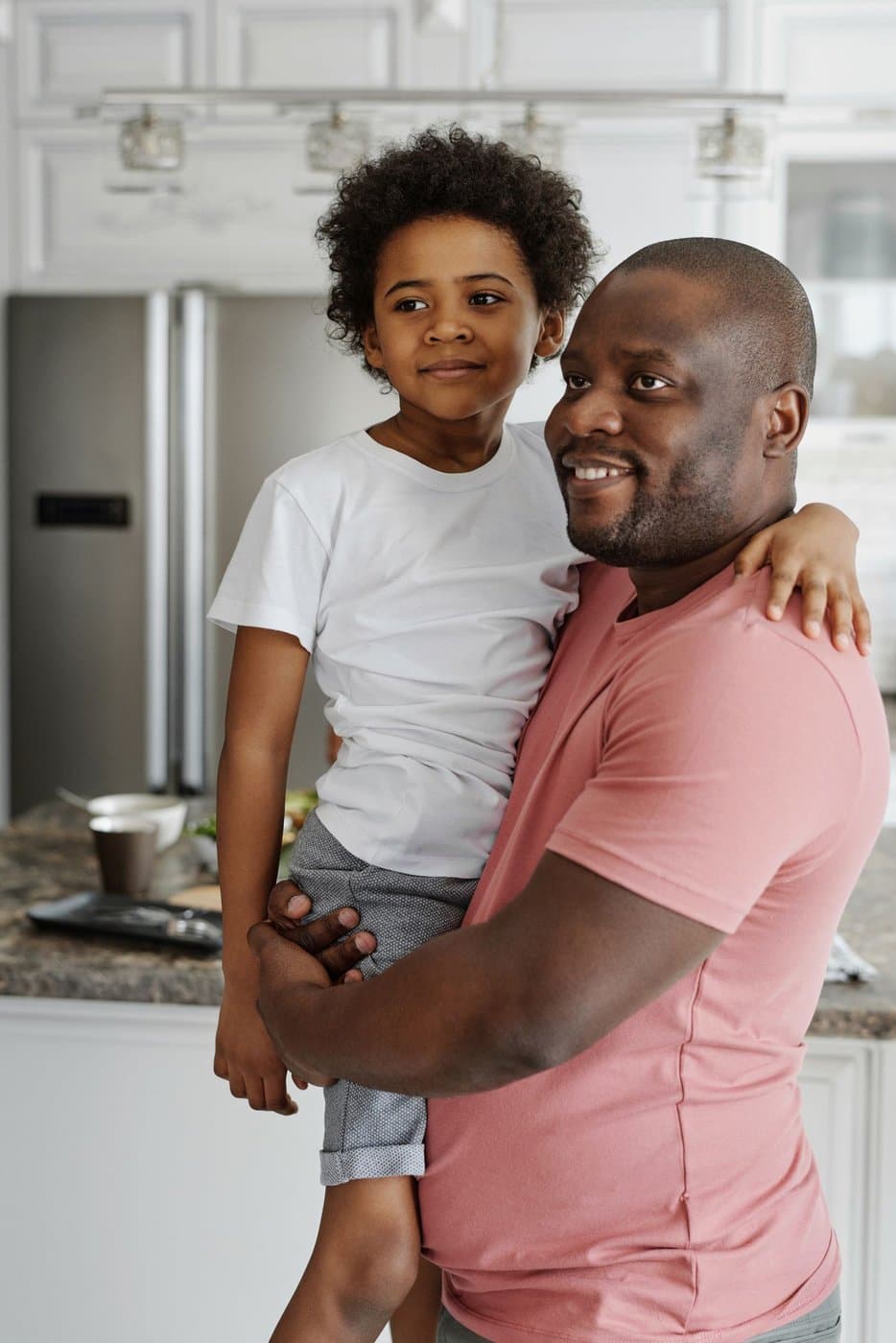 Father holding his son in a bright kitchen before the day begins