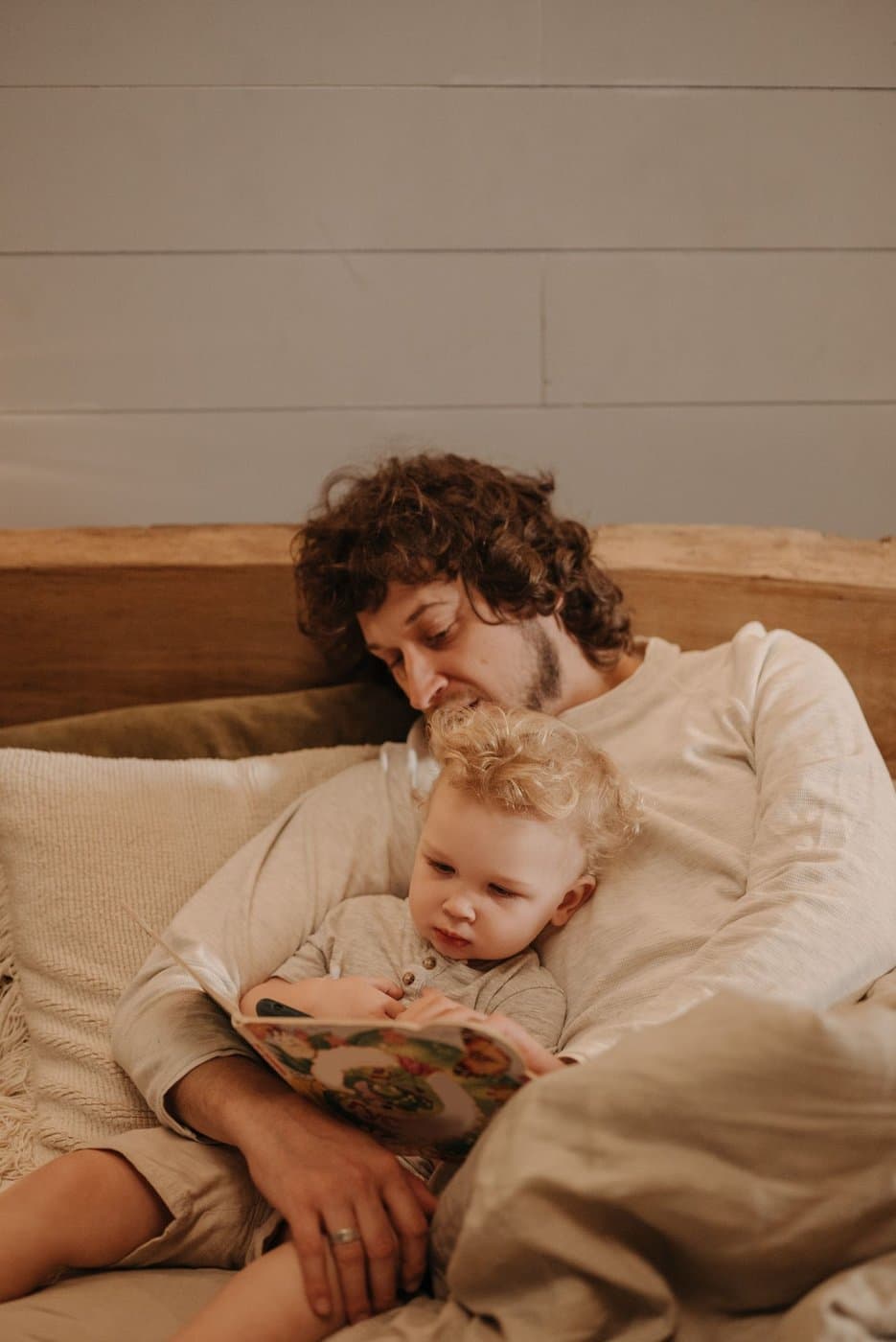 Father reading a book with his young son on the bed