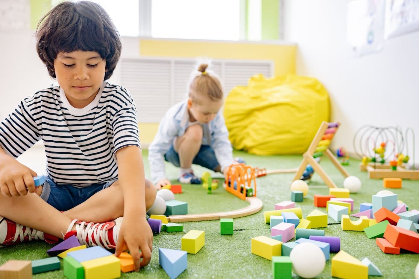 Parent watching a toddler play with wooden blocks on the floor
