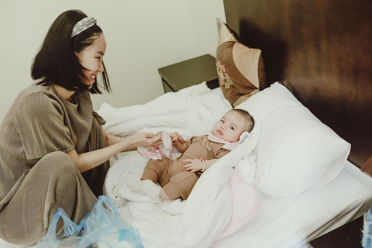 East Asian mother sitting with her baby on the bed at home
