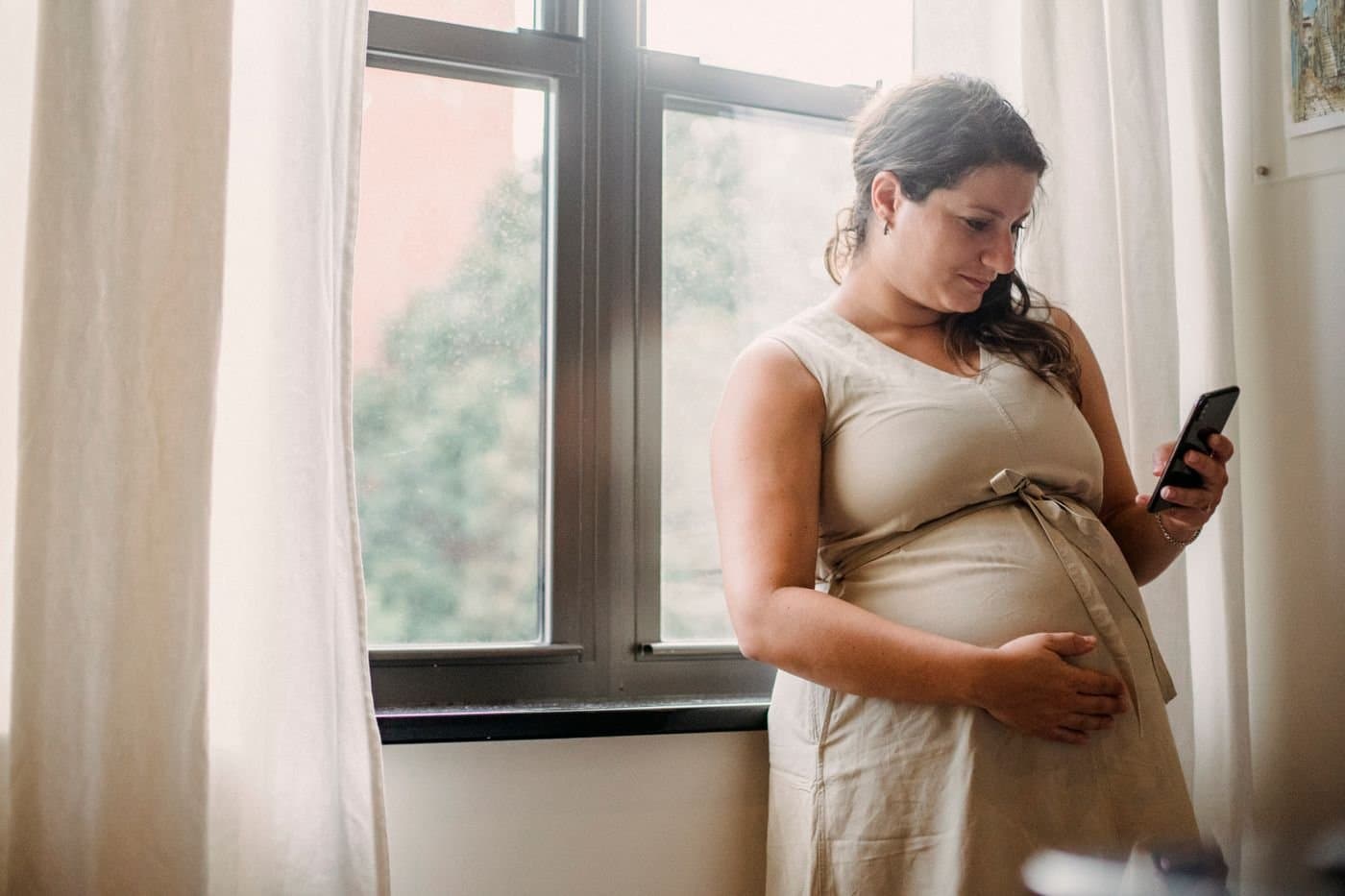 Pregnant woman standing by a window in soft natural light