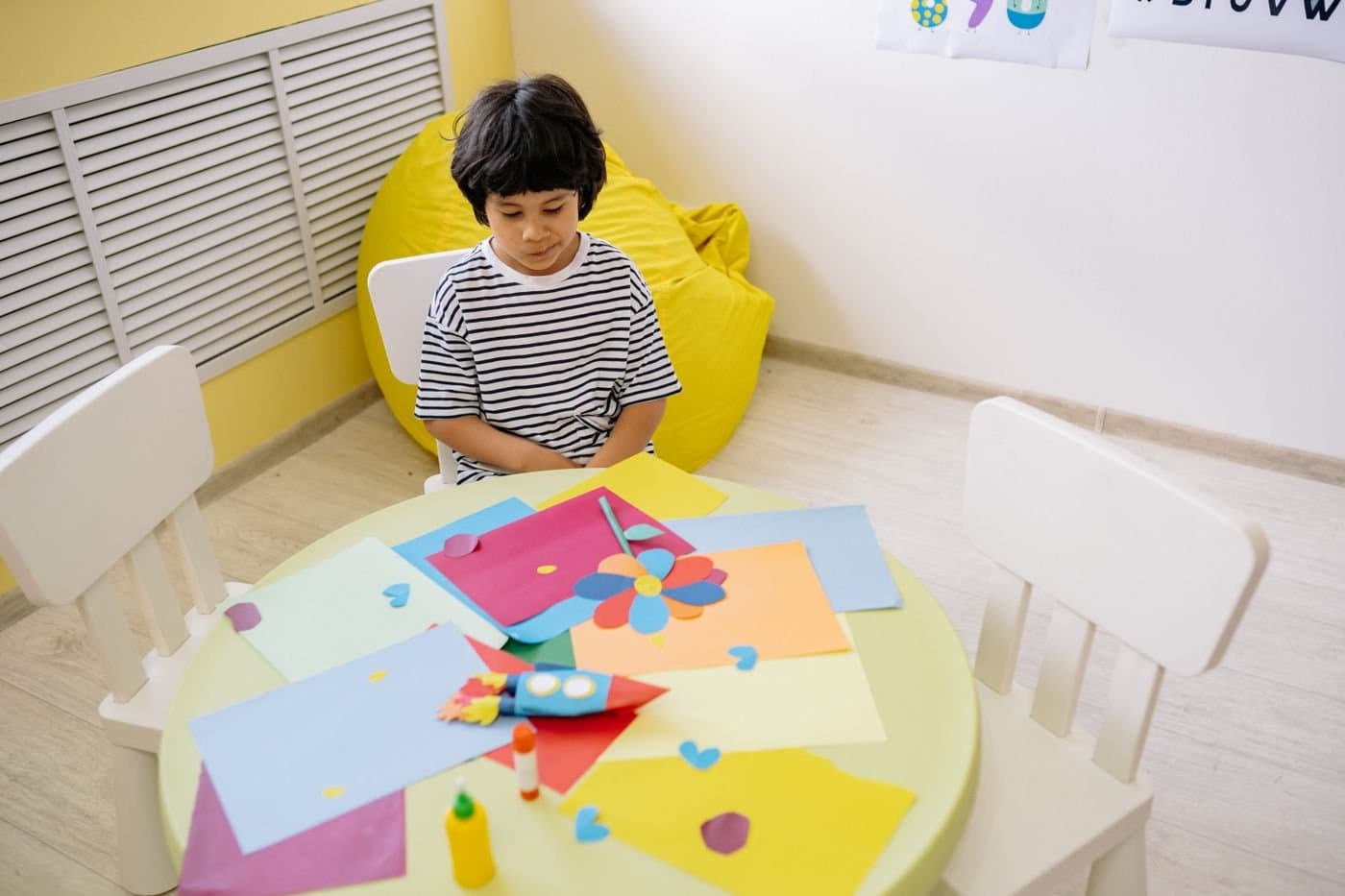 Child doing crafts at a small table in a bright playroom