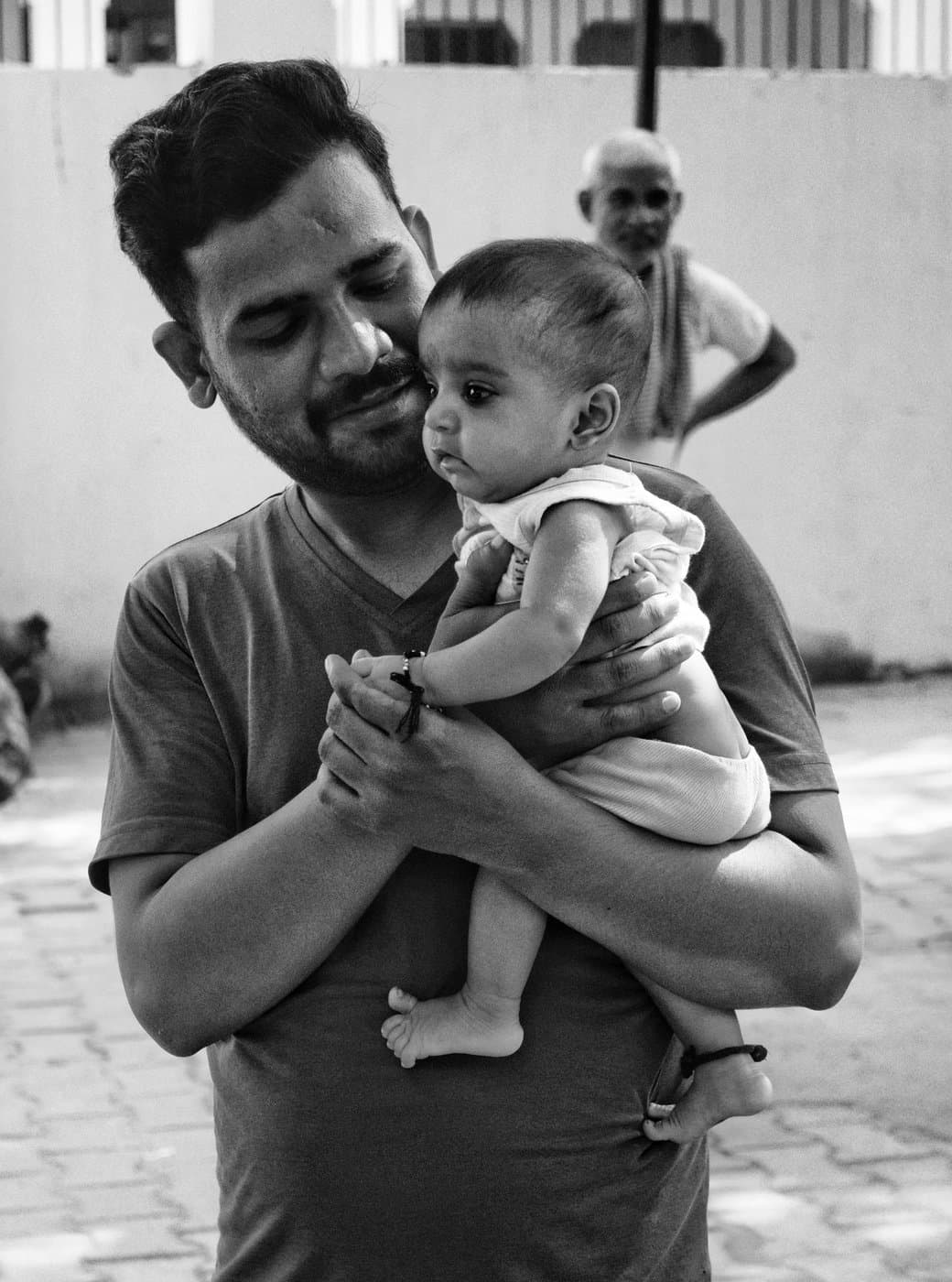South Asian father cradling his newborn baby while a grandfather smiles nearby