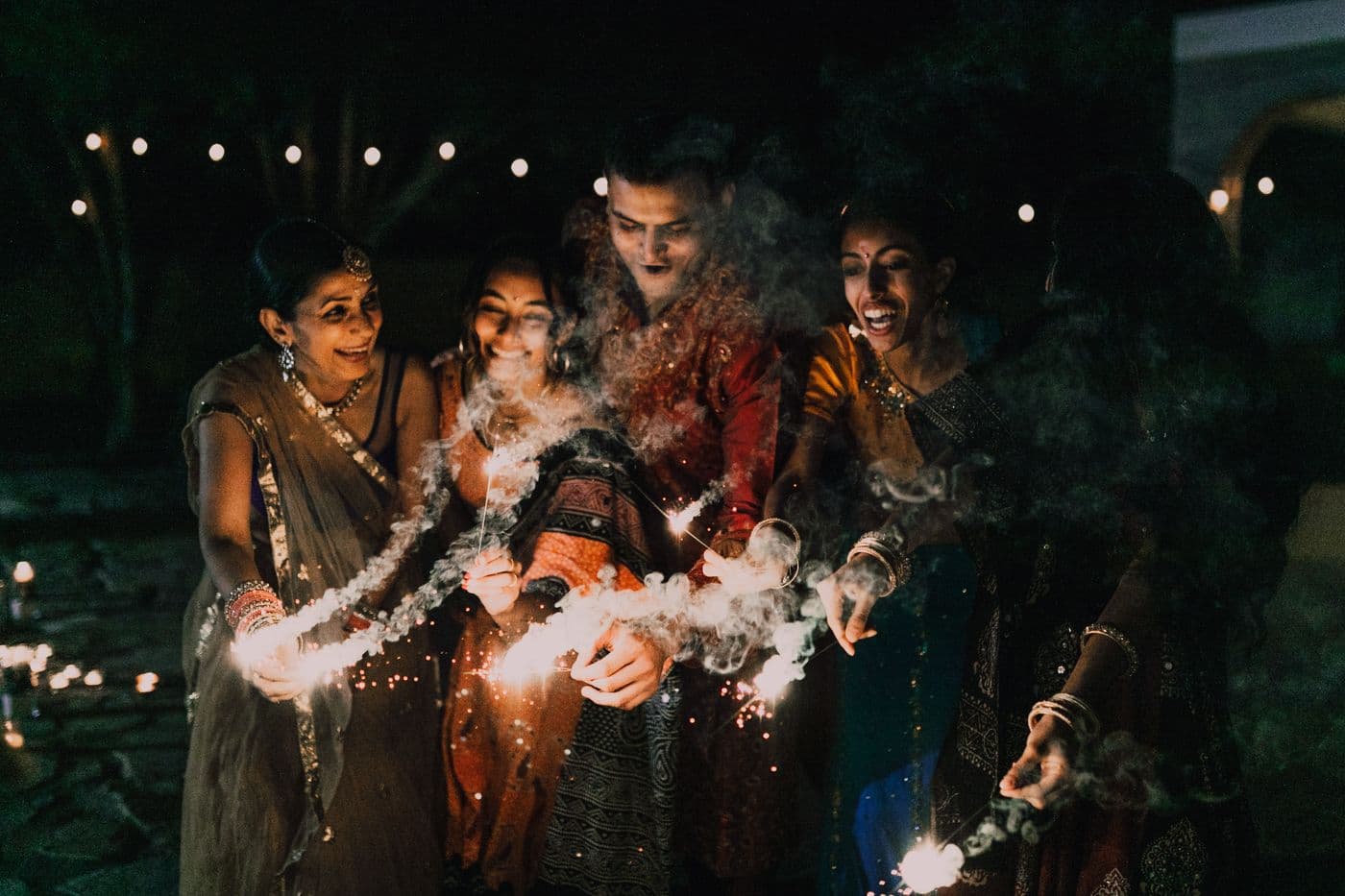 South Asian family celebrating together outdoors with sparklers at a festive gathering