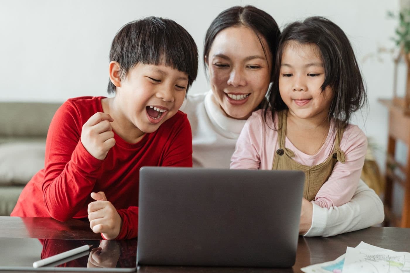 Mother laughing with her children while they use a laptop together