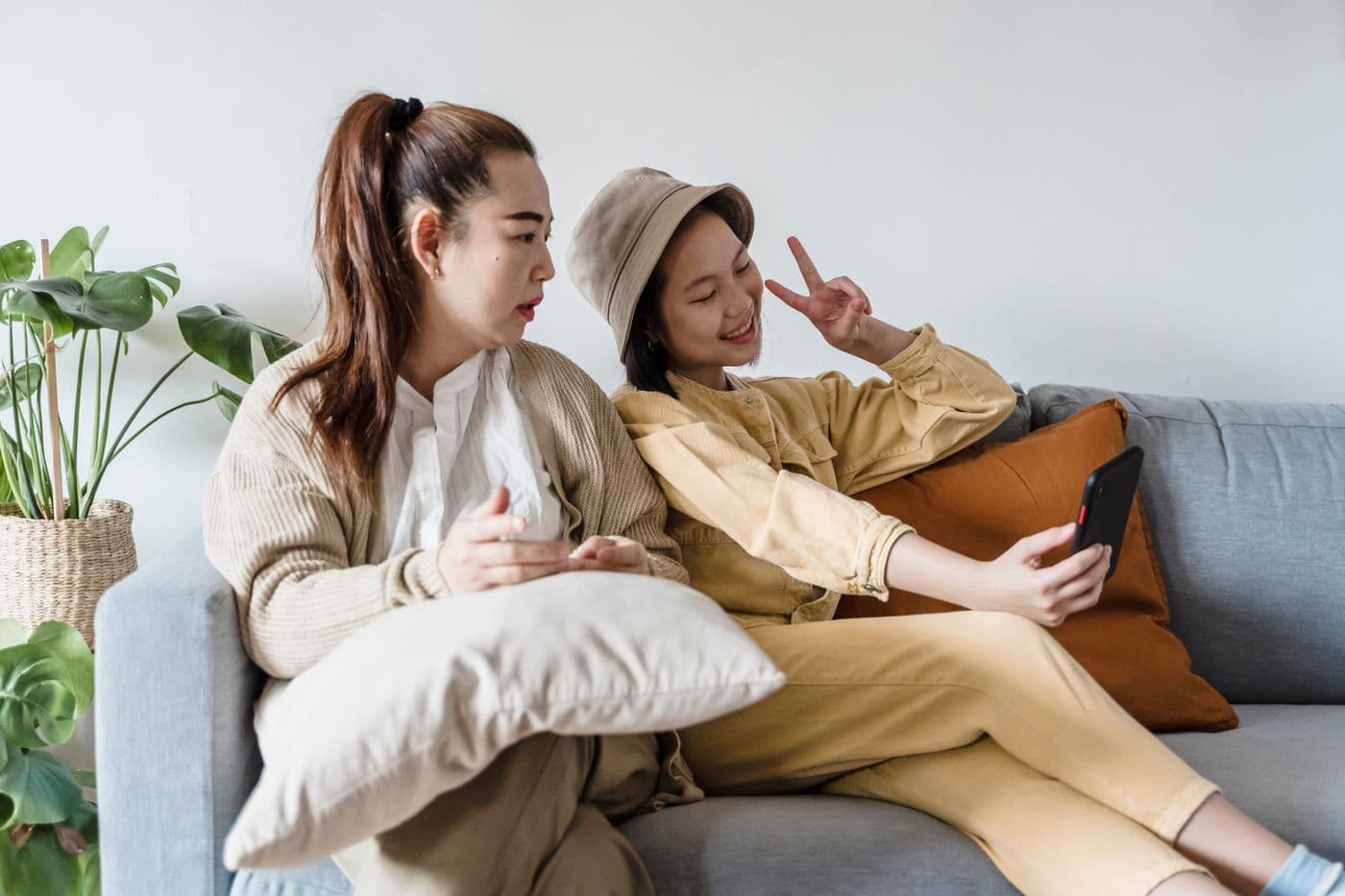 South Asian teenage girl and her mother sitting together at home with a smartphone