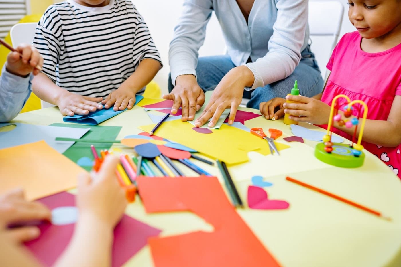 Children doing a group craft activity with an adult at the table