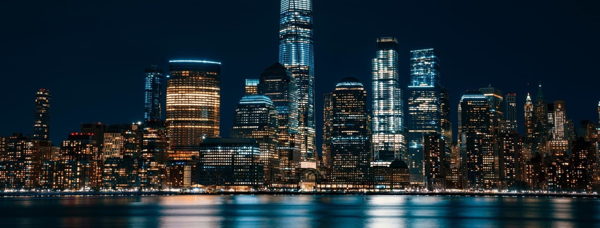 Lower Manhattan night skyline with the World Trade Center reflected in the water