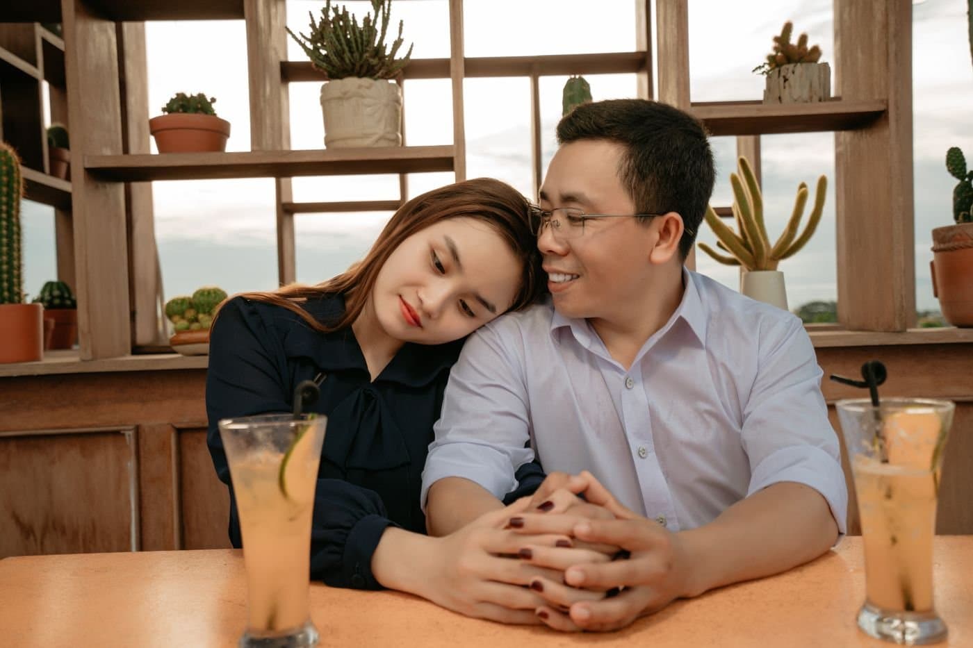 East Asian couple sharing a quiet cafe date with drinks on the table