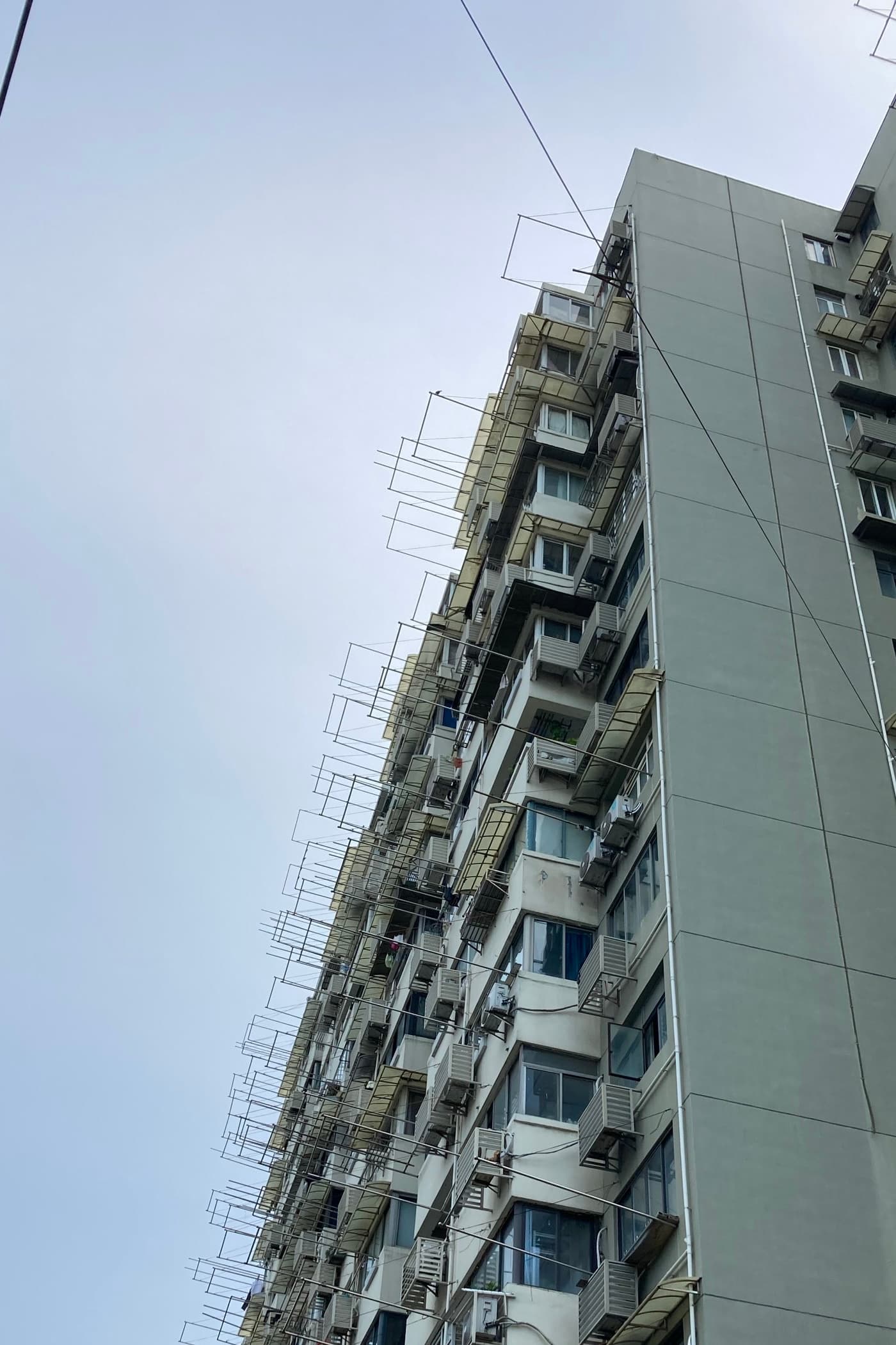 Tall Shanghai apartment building with laundry racks and air-conditioning units, no people in frame