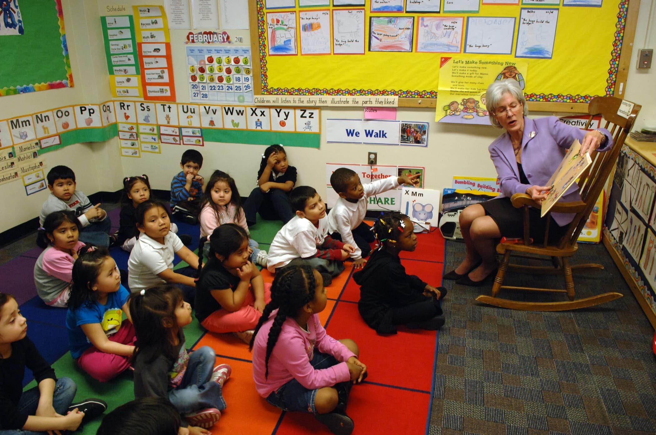 Preschoolers sitting on a classroom rug while a teacher reads aloud in a Head Start early learning center