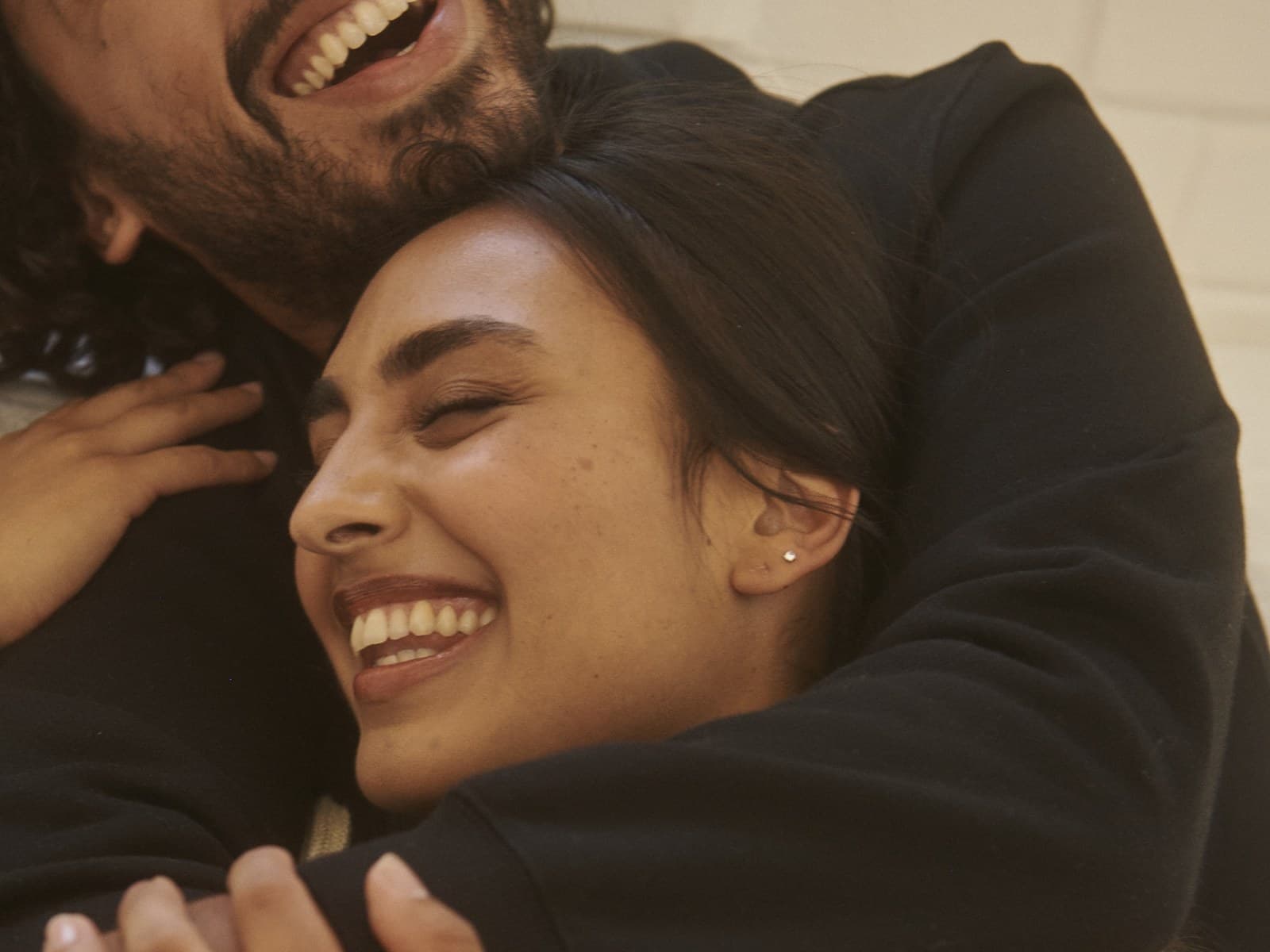 Young couple laughing together in a close embrace indoors