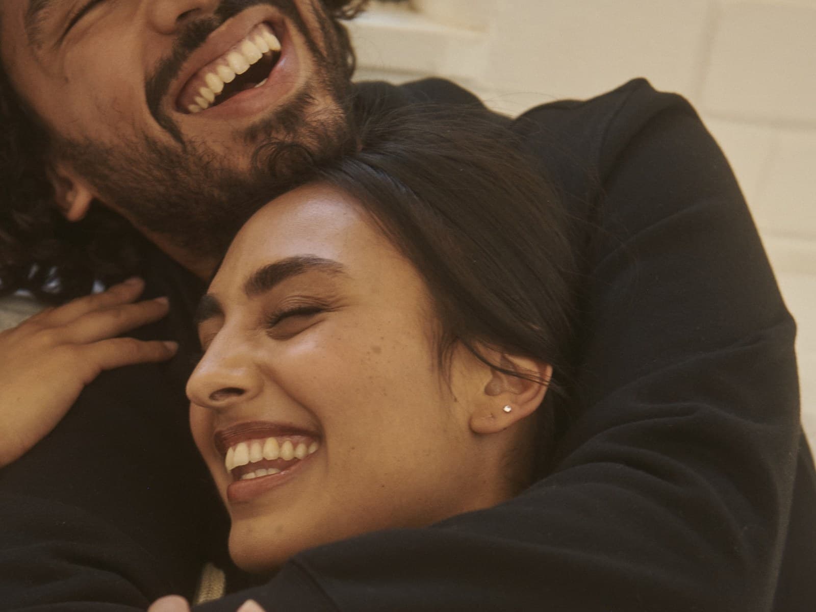 South Asian couple laughing together in a close embrace