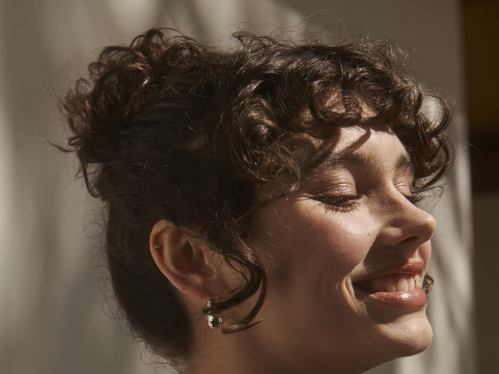 Young woman smiling with eyes closed in warm sunlight