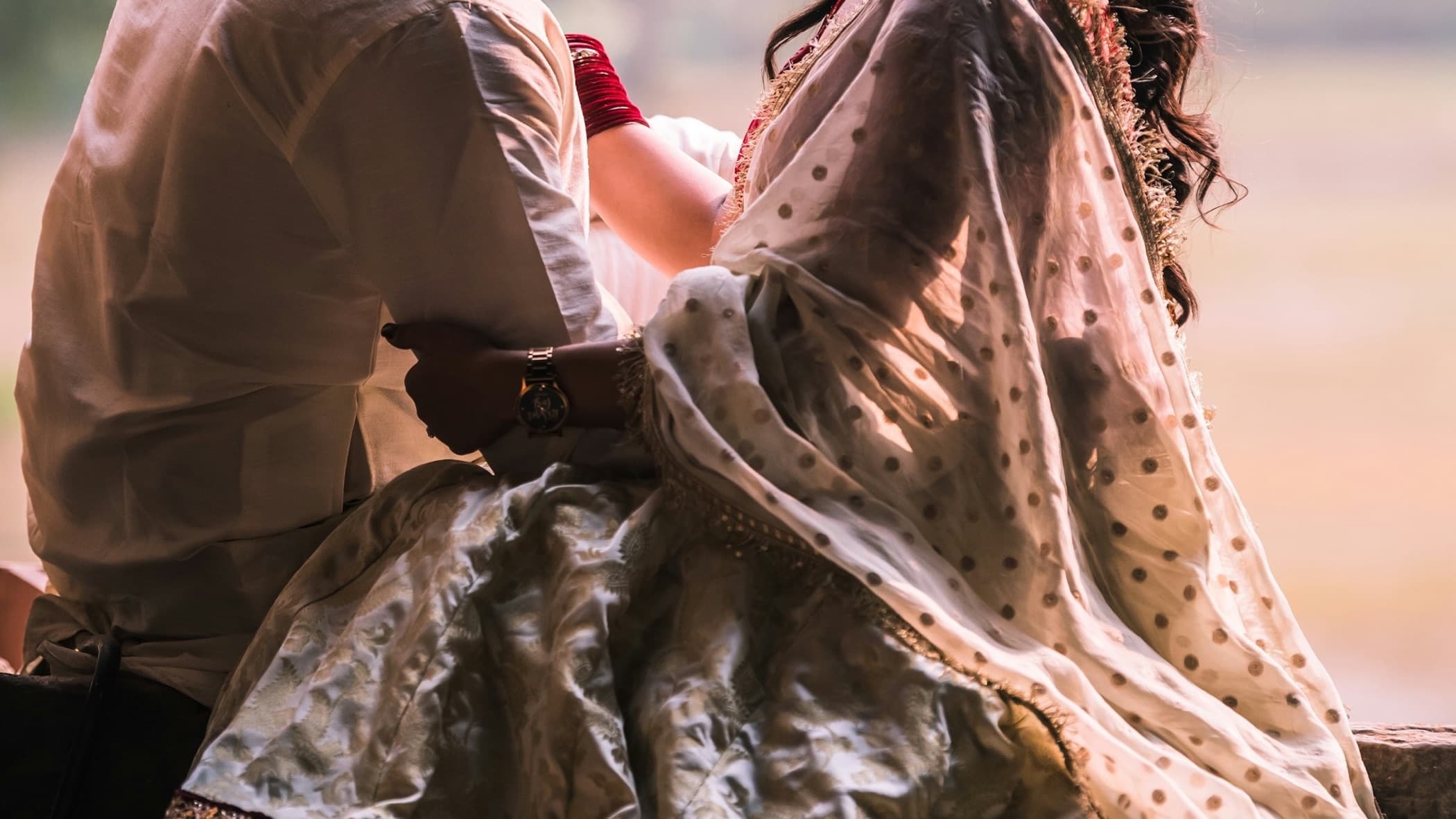 South Asian couple in traditional wedding clothes looking at each other