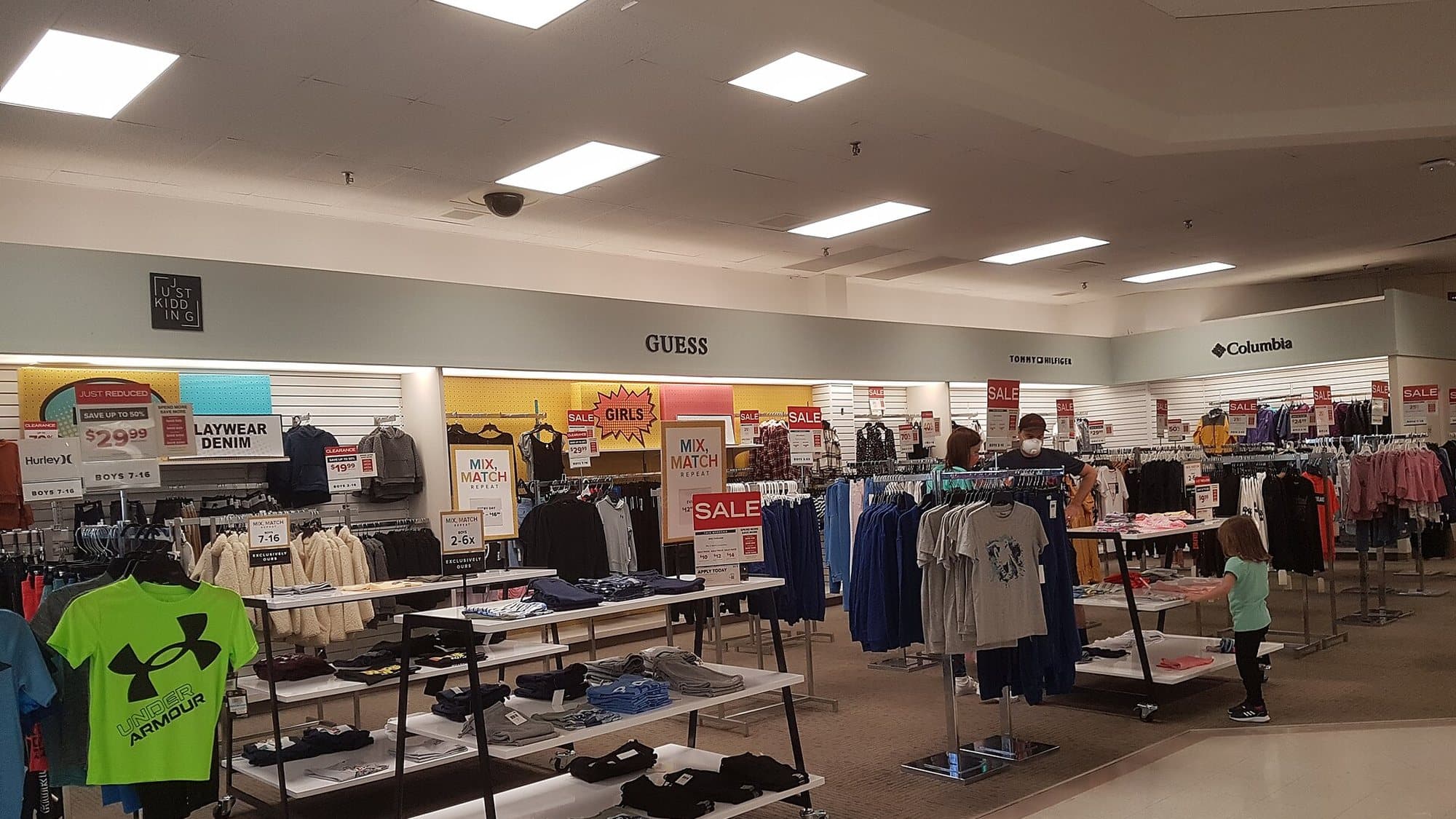 Kids clothing racks and sale tables in a department store, with mix-and-match signs and folded playwear