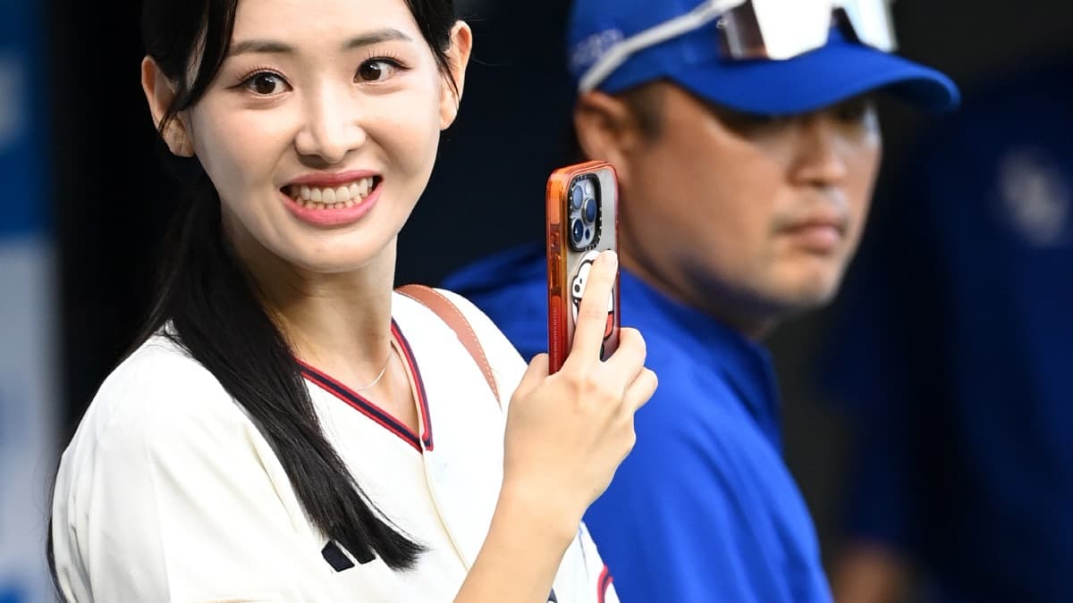 Kim Da-young smiles at a baseball stadium while holding up a phone
