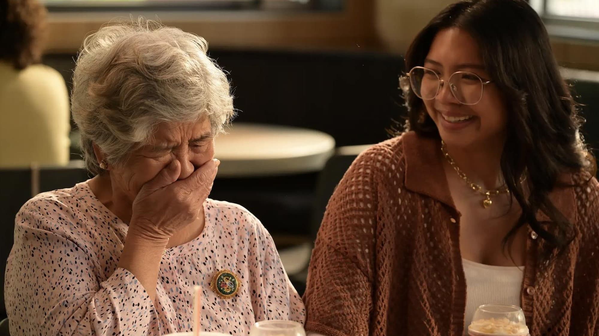 Filipino American granddaughter Aina and her lola Herecilla sharing an emotional moment at a table during McDonald's Sweet Connections campaign