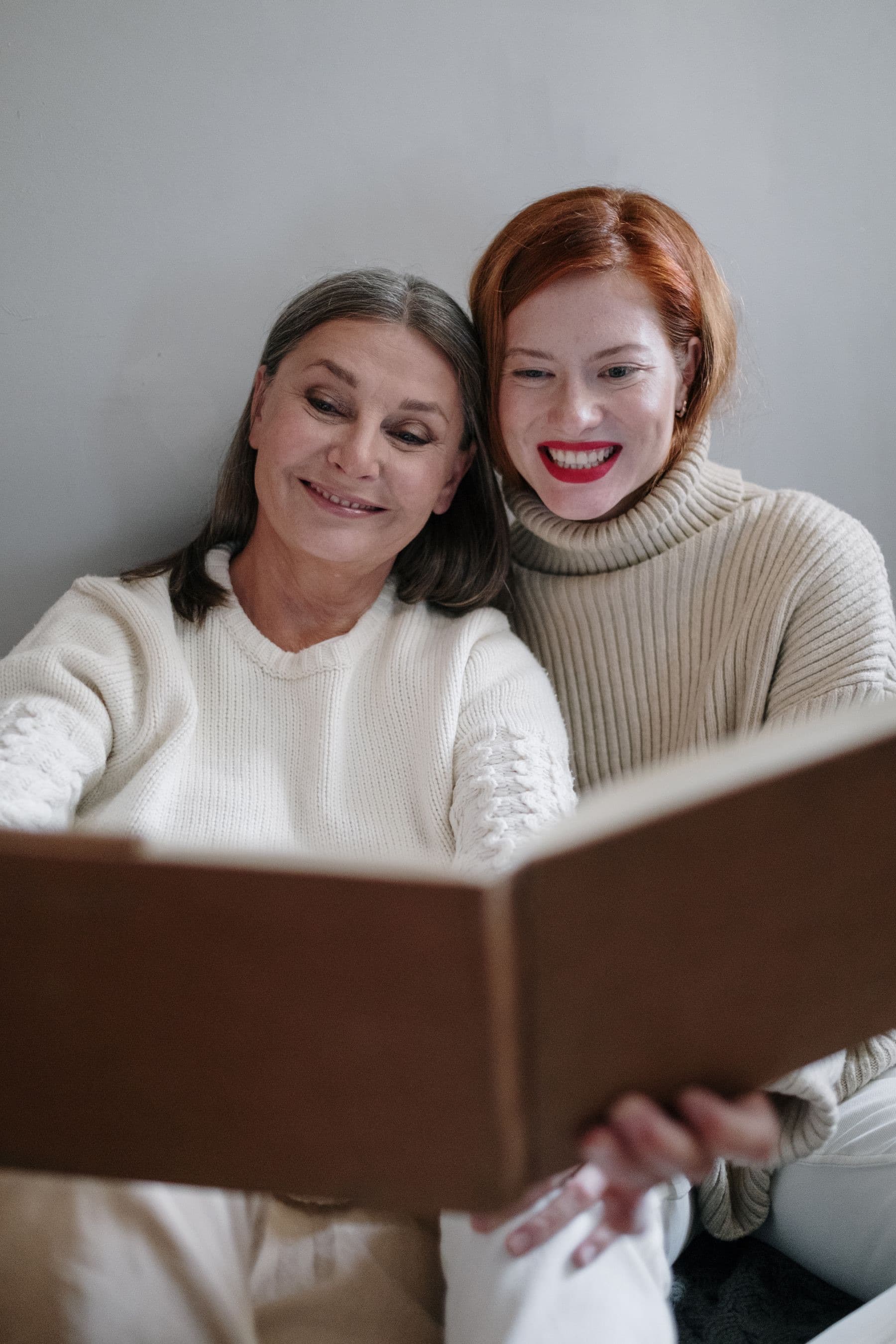 An older woman and a younger woman smile with their heads together