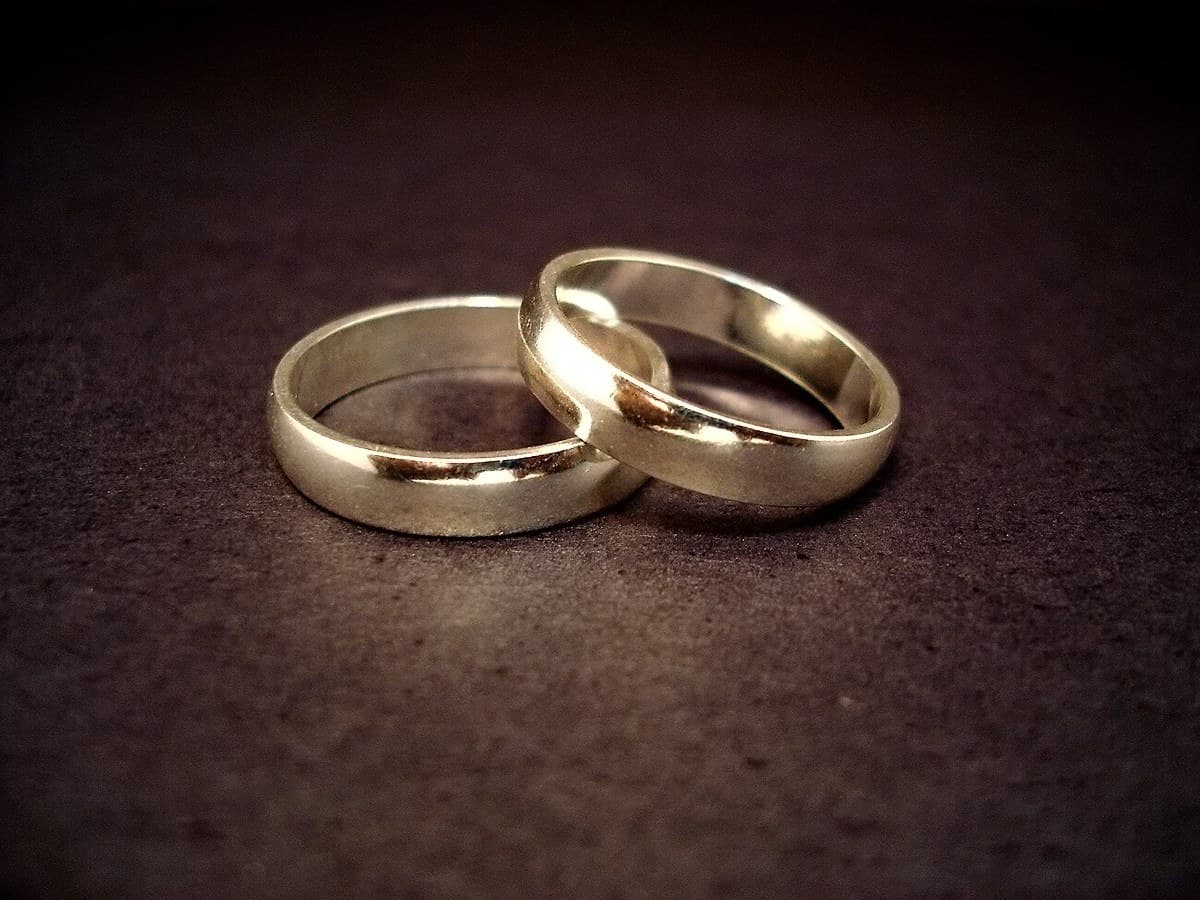 Two gold wedding rings resting together on a dark surface