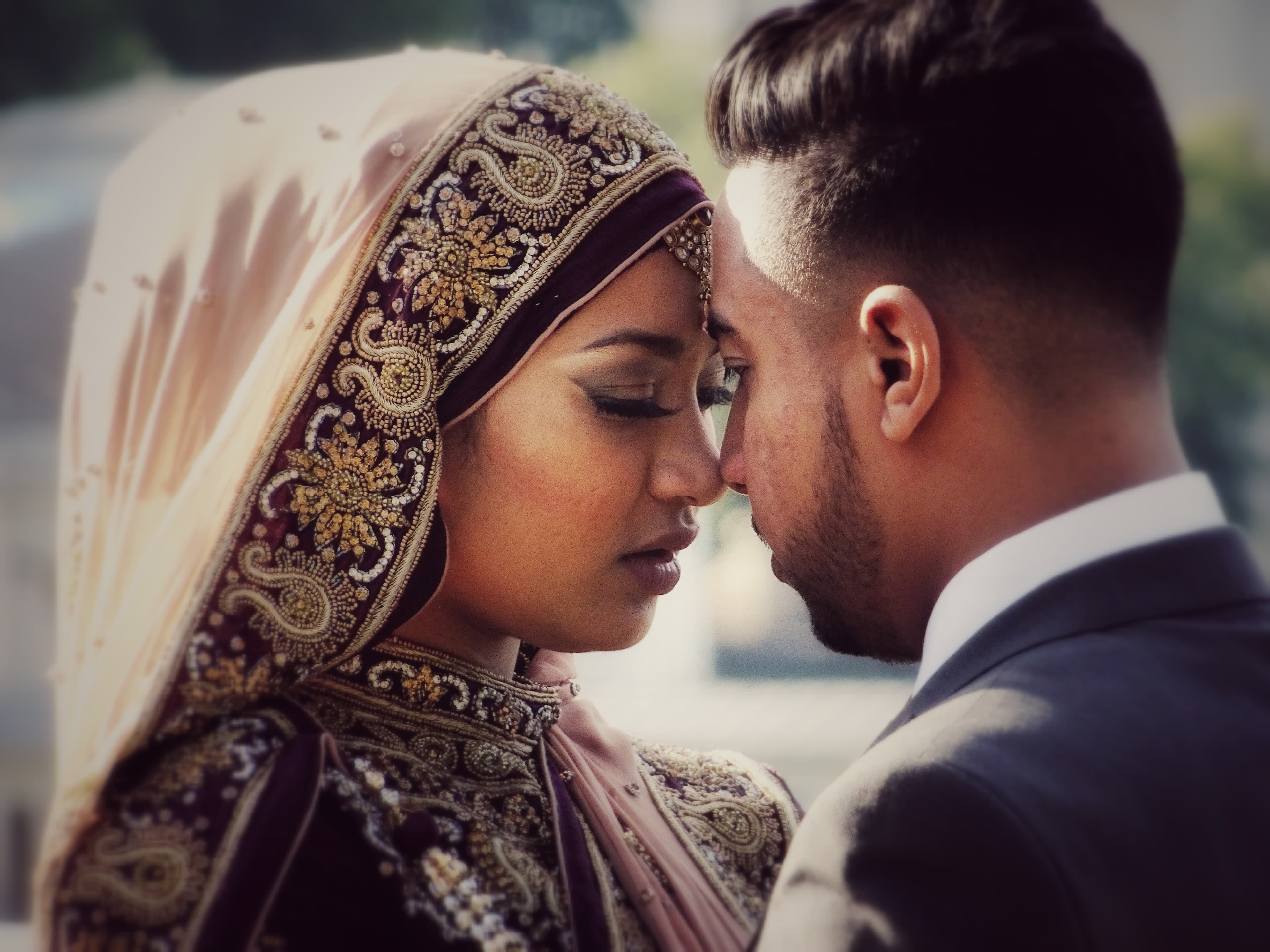 Young Asian couple in formal attire resting forehead to forehead during an outdoor photoshoot