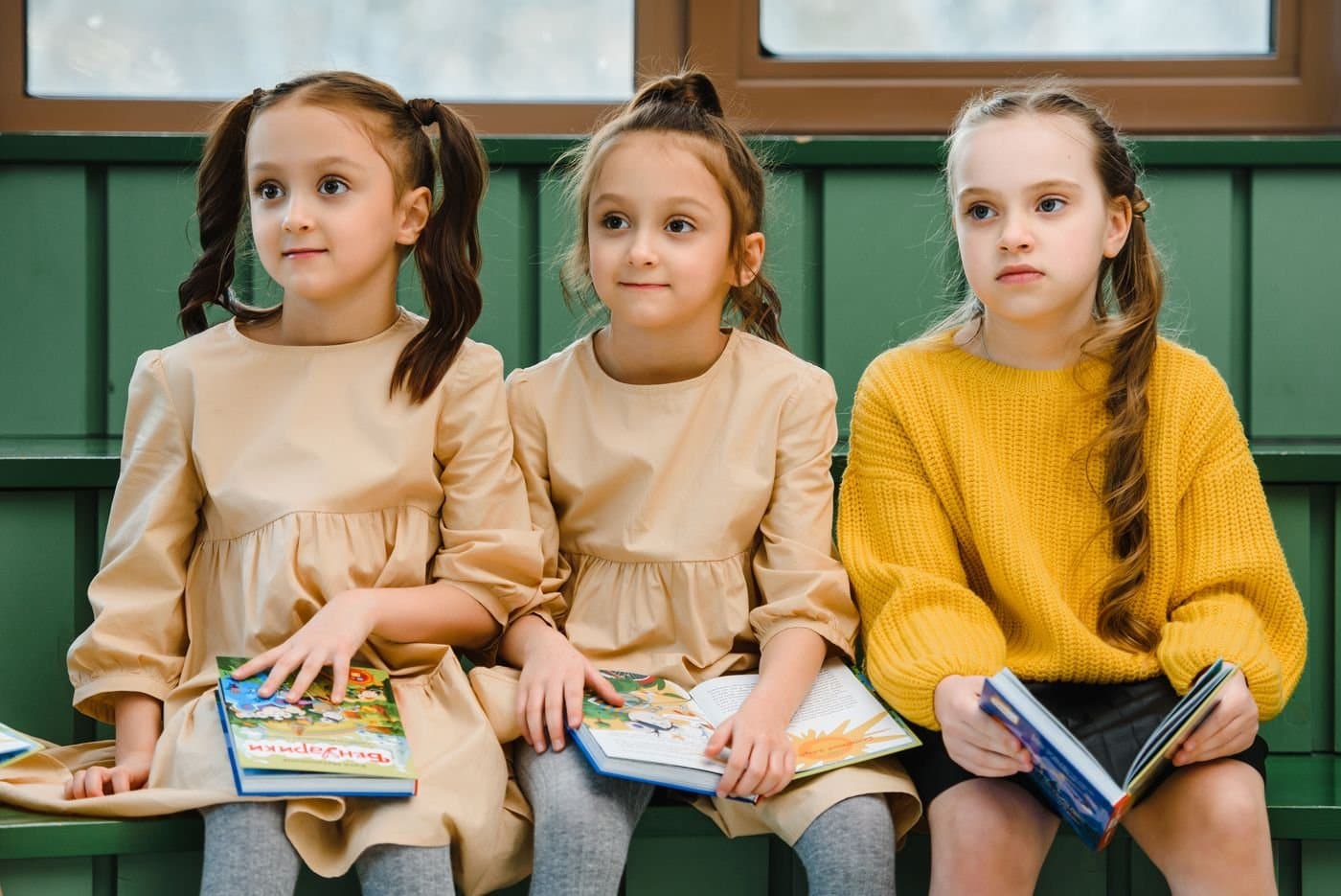 Young girls reading books together on a bench at school
