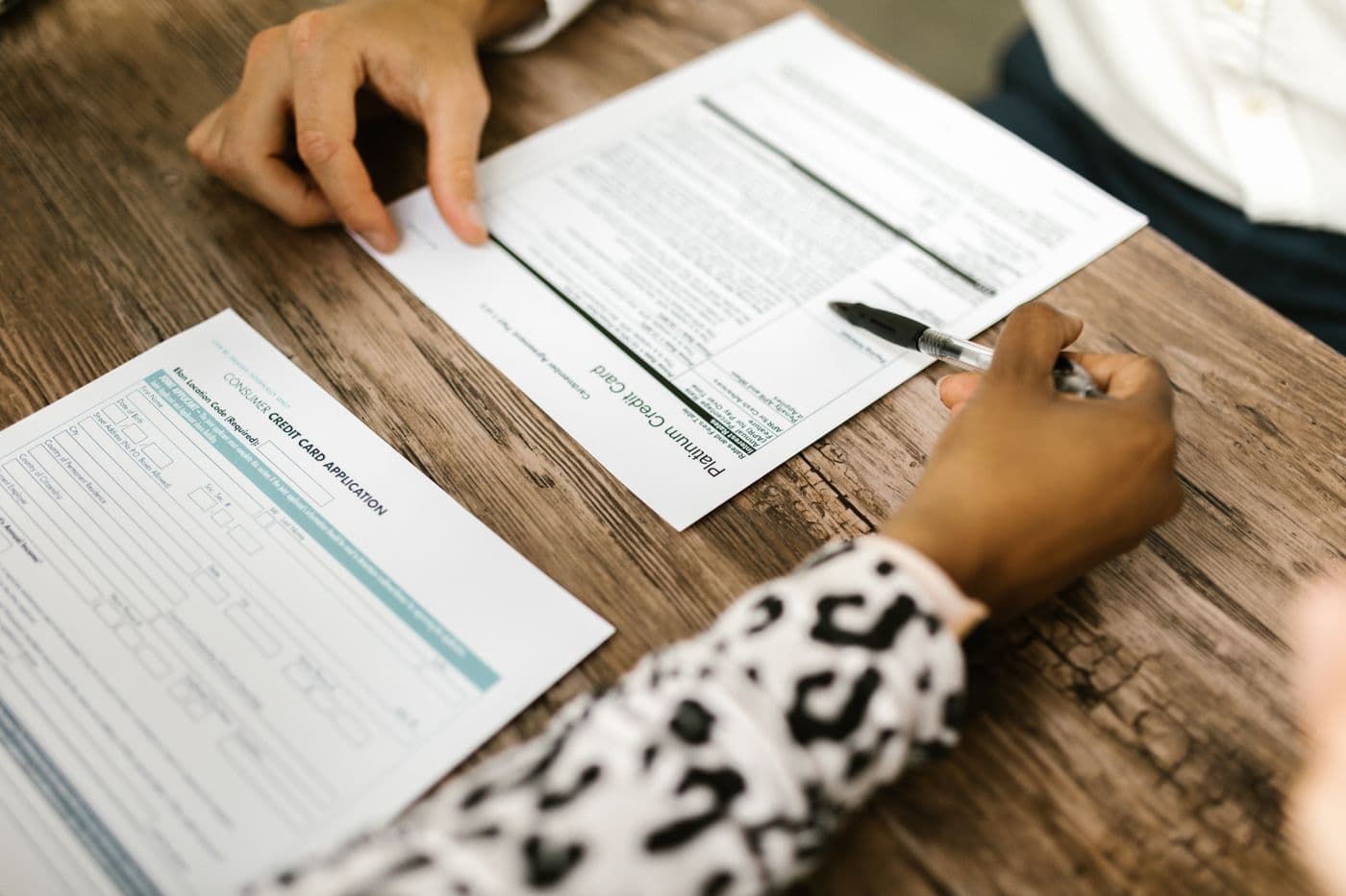 Hands reviewing credit and planning documents at a desk