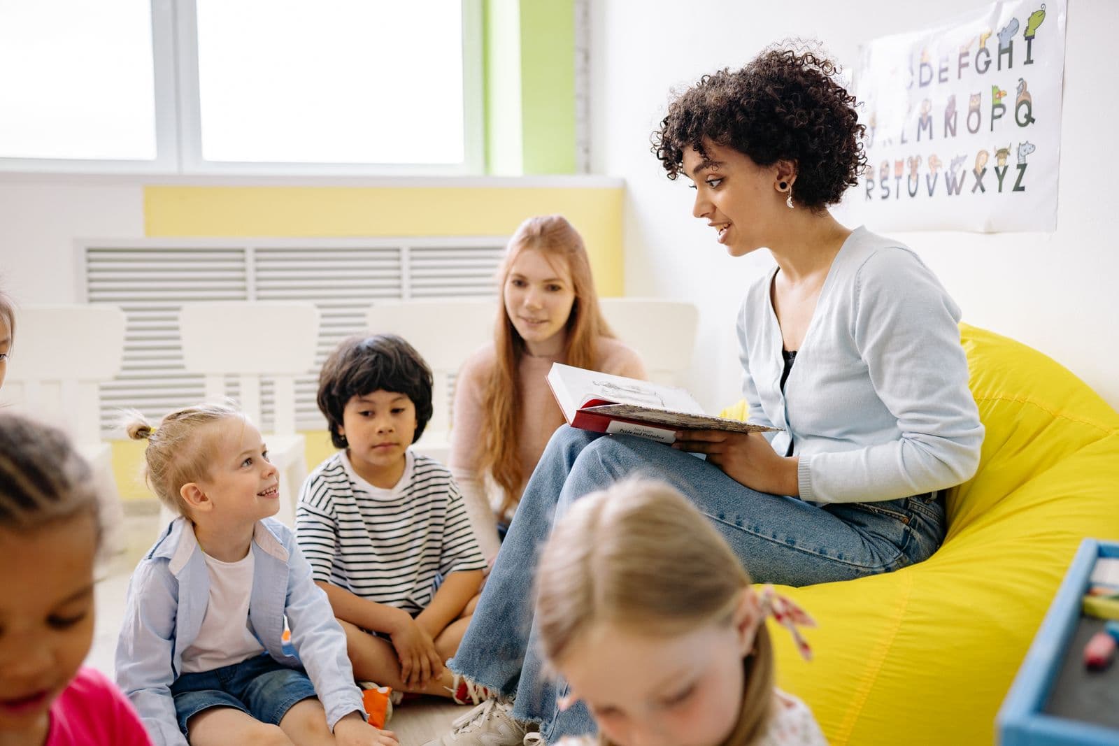 Teacher reading with a diverse group of preschool children in a bright classroom