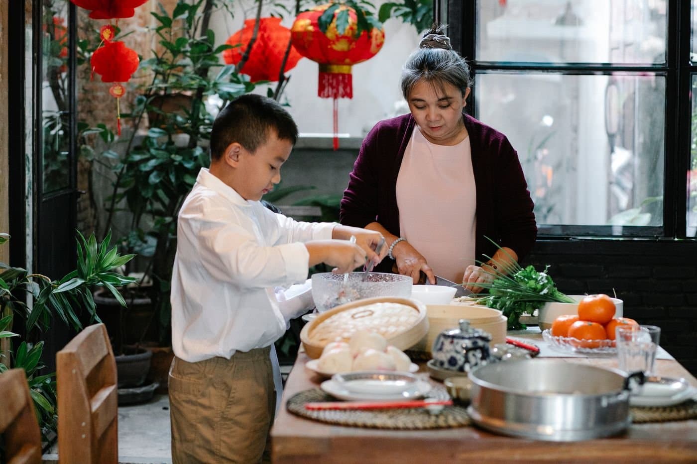 Grandmother teaching a child to prepare food for a Lunar New Year meal