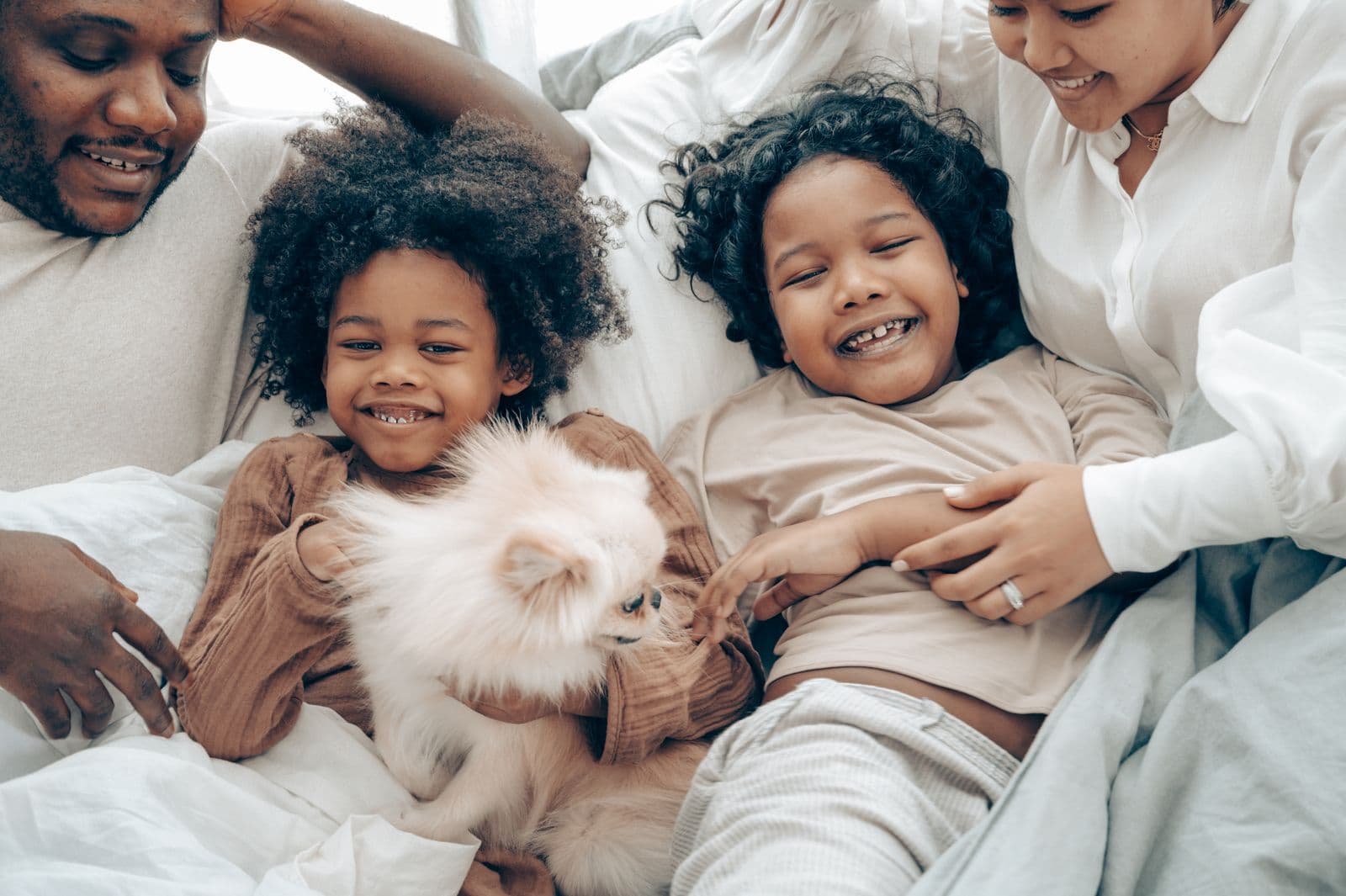 Multicultural family laughing together on the bed at home