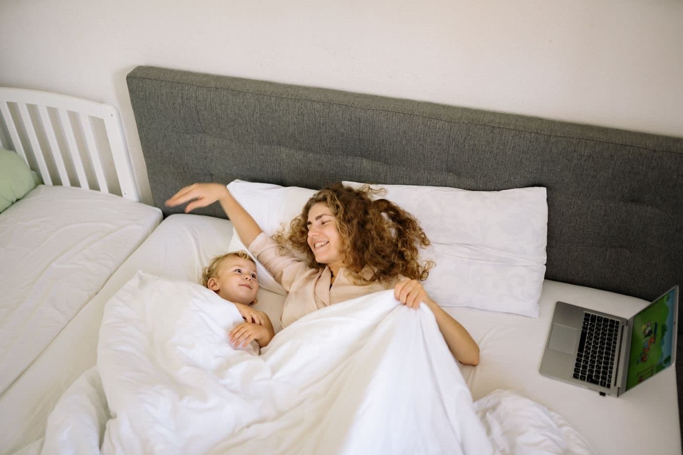 Mother and toddler relaxing together on a bed in the morning